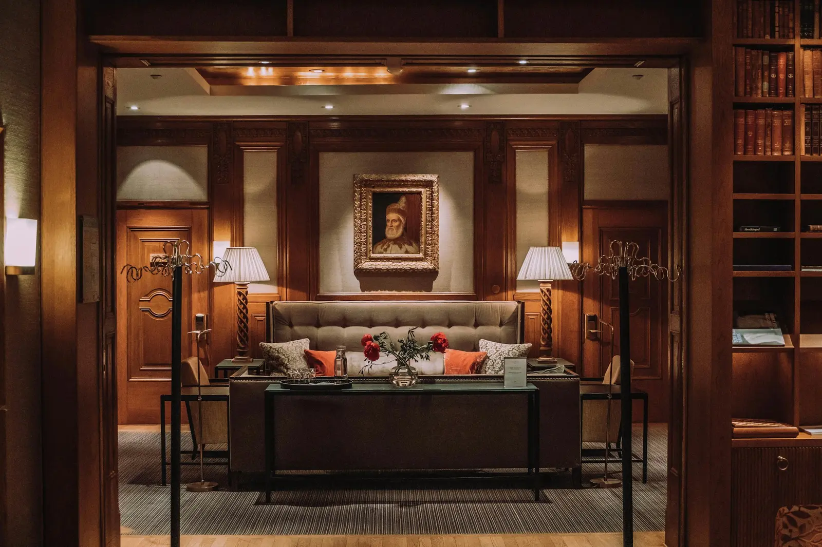 Sala de estar de hotel con revestimientos de madera, sofá tapizado y alfombra