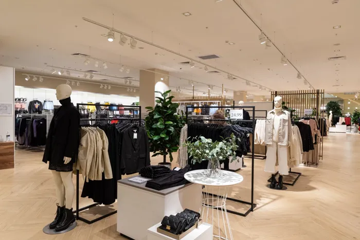 Tienda de moda con mobiliario de exposición y recorridos entre secciones