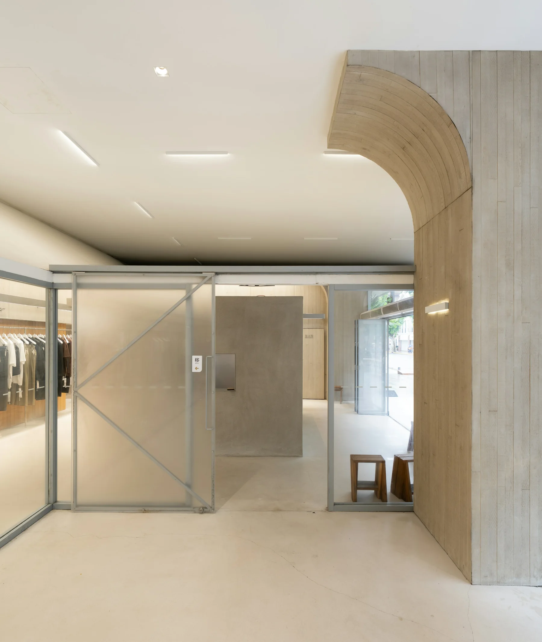 Espacio comercial con arco de hormigón y mamparas de vidrio