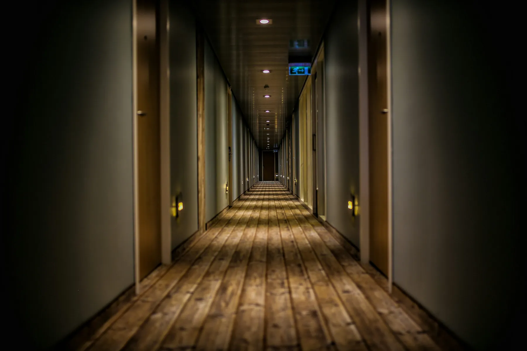 Pasillo de hotel con pavimento de madera e iluminación a baja altura
