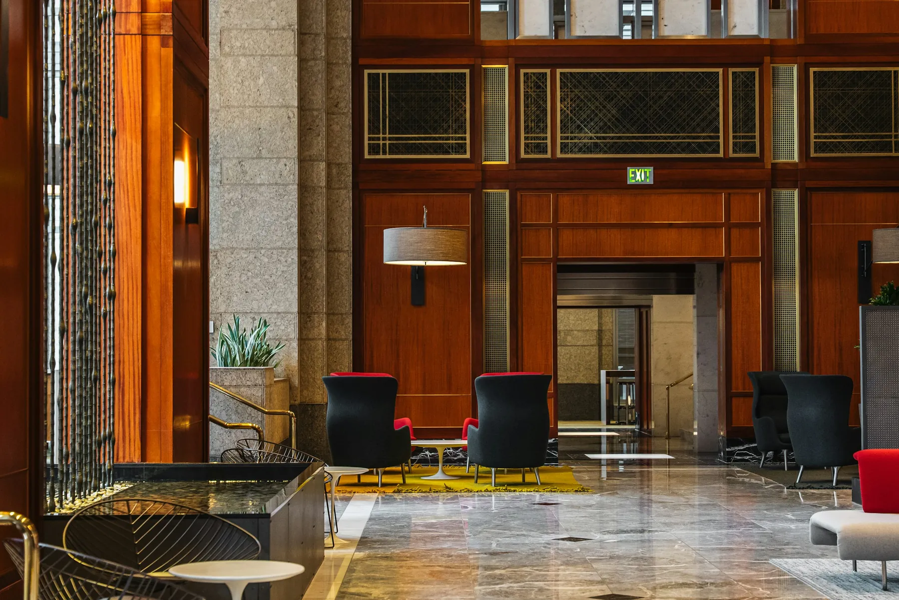 Vestíbulo de hotel con revestimiento de madera, columnas de piedra y butacas